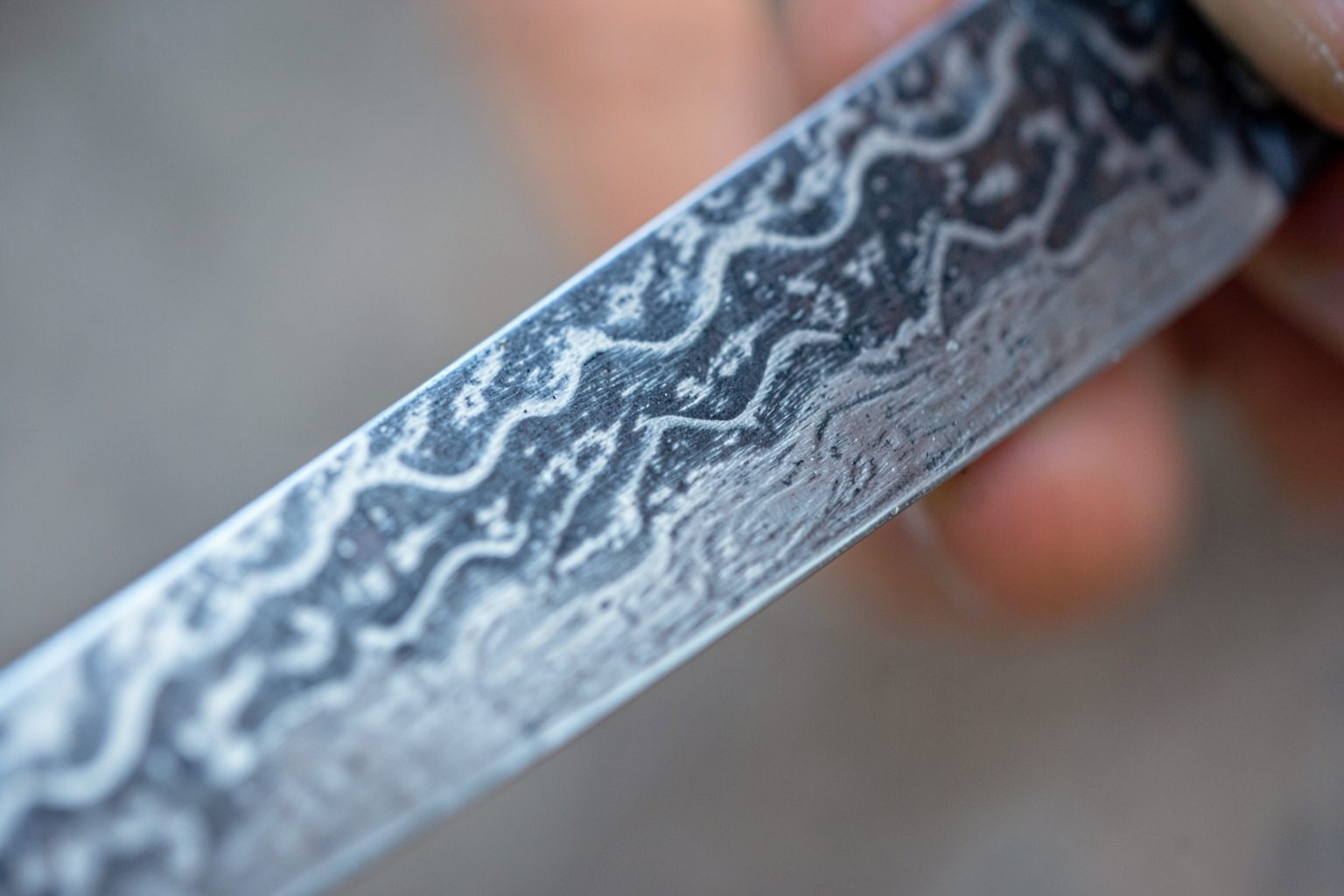 Close-up of a damascus chef's knife blade showing its layered steel pattern